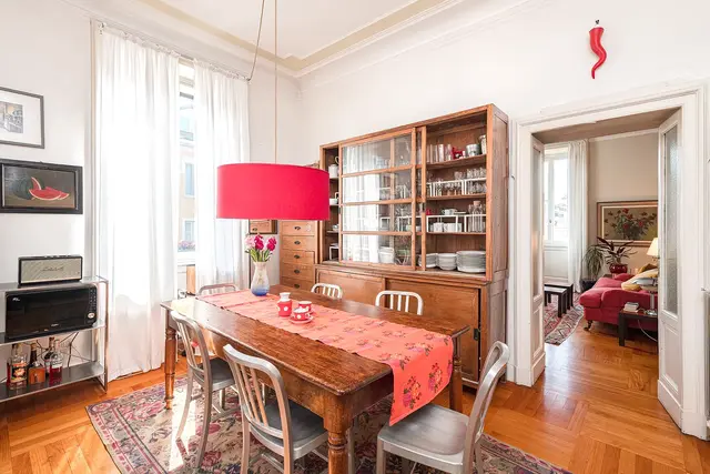 Sala da pranzo con tavolo in legno e dettagli rossi